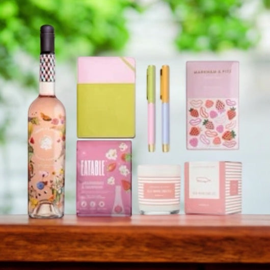 Gift box containing Summer In a Bottle Rose with vegan leather journal, pens, artisan chocolate, popcorn and candle.