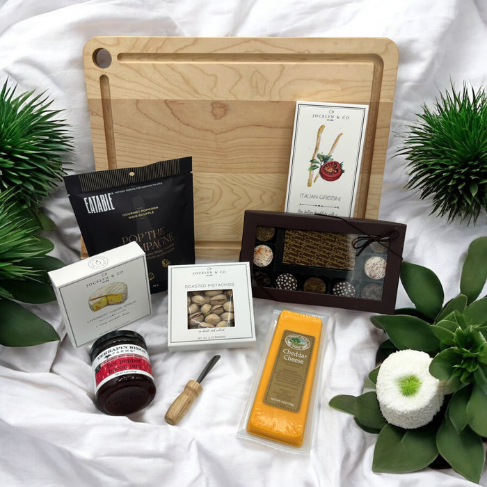 Congrats gift includes cutting board, assorted cheeses, crackers, cutting knife, jam, popcorn, nuts and Congrats chocolates.