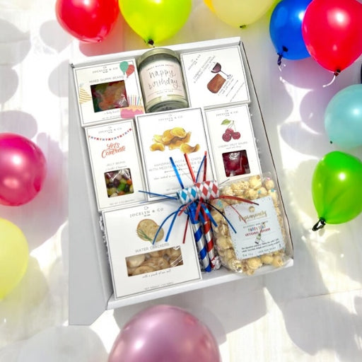 Birthday gift box containing assorted candies, potato chips, cheese, crackers and popcorn.