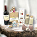 Housewarming gift box filled with wine, cheese board, crackers, cheese, jam, dish towel, house candle and oil & vinegar jars.